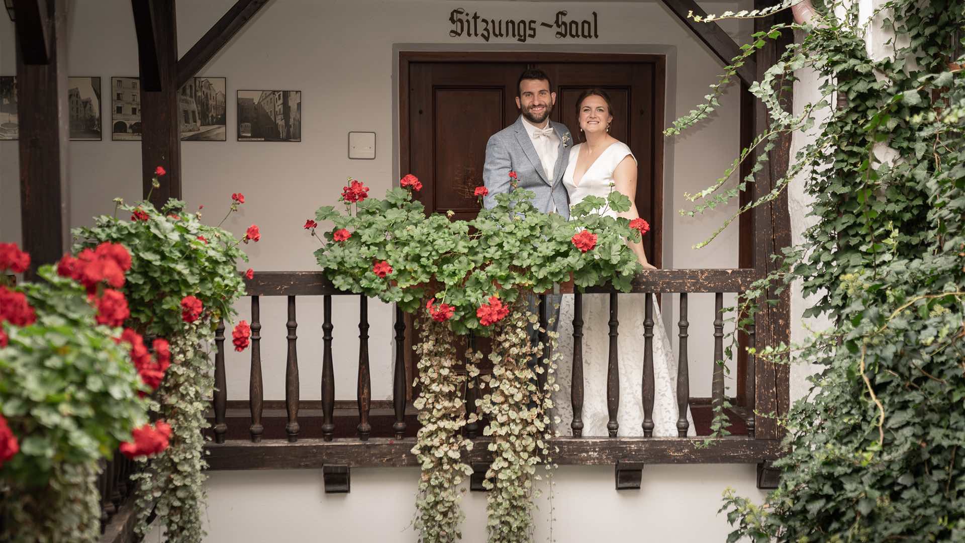 Hochzeitspaar steht auf Balkon mit Blumen